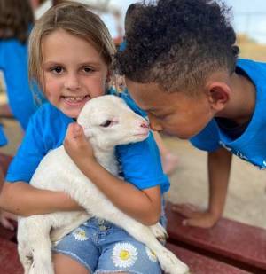 Children enjoying their field trip to a farm and meeting a baby goat.