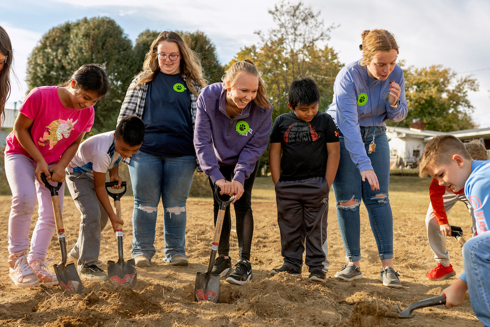 Tennessee Tech students in green stickers, from left, Madisen Hess, Trinity Parrish and Abbi Miller, teach hands-on gardening to students at Jere Whitson Elementary.