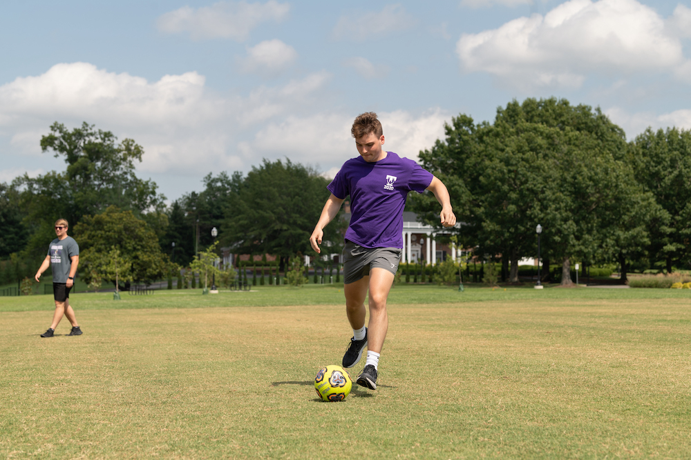 A student kicks a ball in Walton Park.