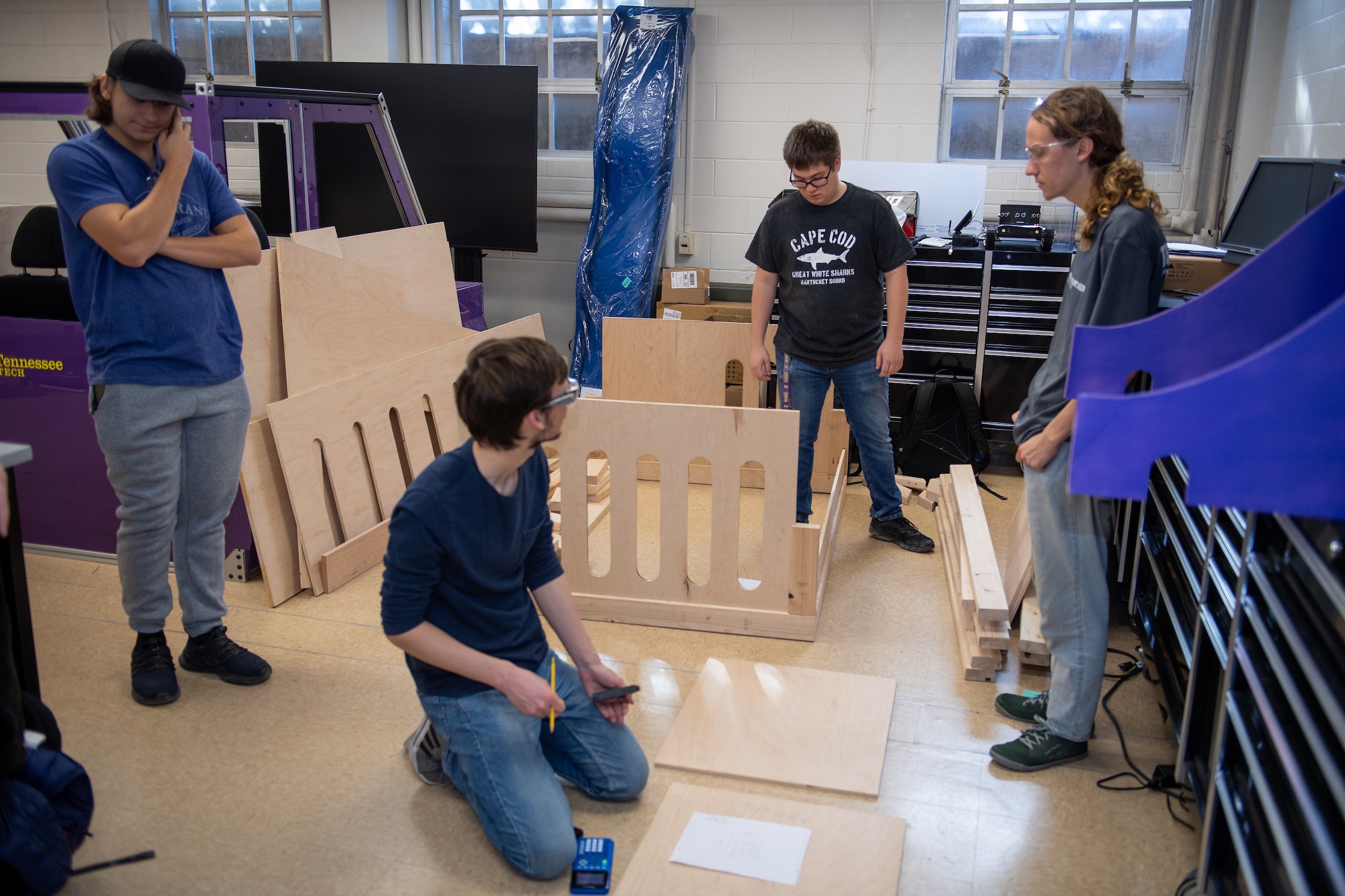   Tennessee Tech Engineering for Kids team members, standing from left, Frederick Heerdt, Carter Birdwell and Aiden Bull, consult with another team member, Sean Borchers, kneeling, on modifications being made to a climbing play installation being built for a child in Wilson County with autism.